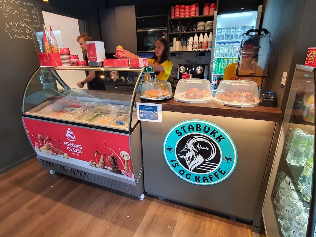 Resepsjonen på Stabukk kafé i Olden. Et turkis skilt har en sta vær som hentyder til navnet på stedet. En iskremfryser står til venstre.