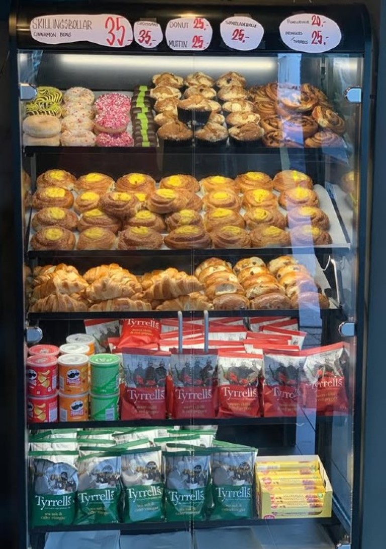 Et glassskap med ferskbakte bakverk, chips og drikke.