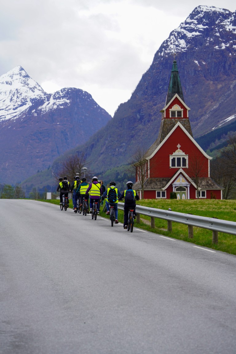 RIB-speedbåttur passerer et P&O-cruiseskip fortøyd i fjorden ved Olden, Norge, med grønne fjellsider bak