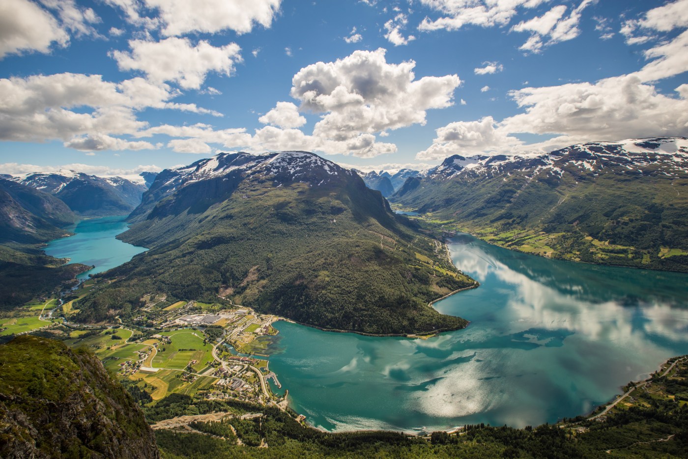 Elsykkelrytter stopper for å fotografere den perfekt speilvendte refleksjonen av Briksdalsbreen og fjellene i Oldevatnet, Olden, Norge
