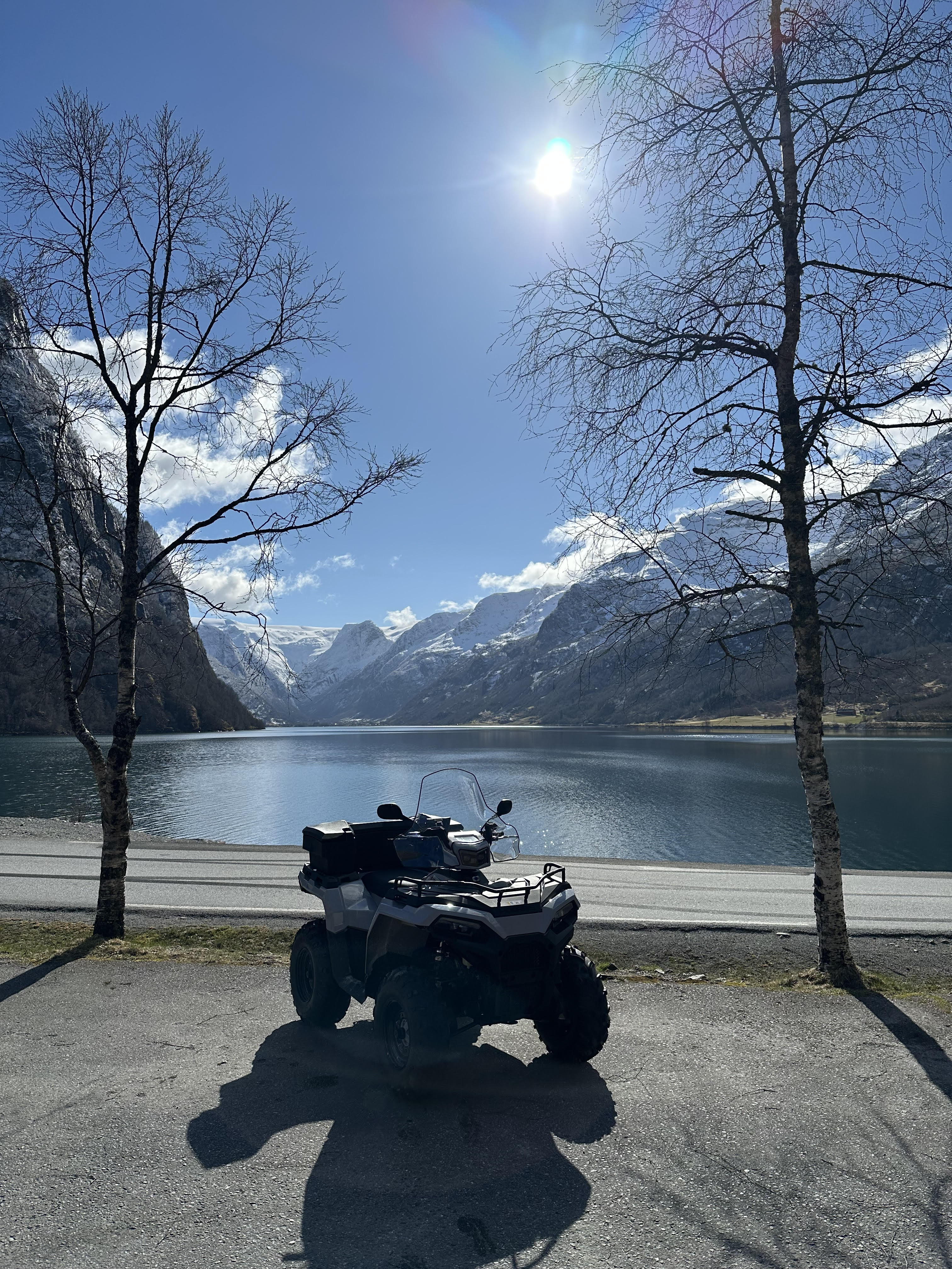 To personer på ATV med fjell i bakgrunnen