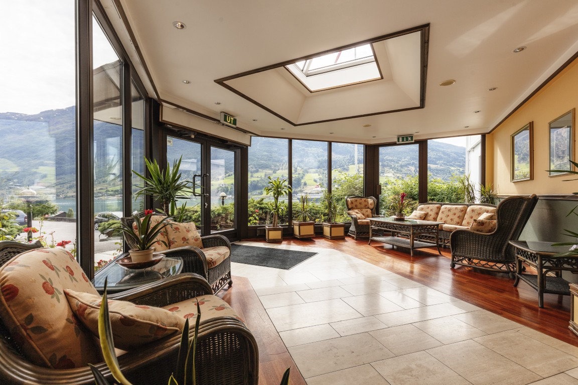 Inngangen til Olden Fjordhotel. Store vinduer gir mye naturlig lys, med et takvindu i taket. Komfortable seter gir et område for avslapning.