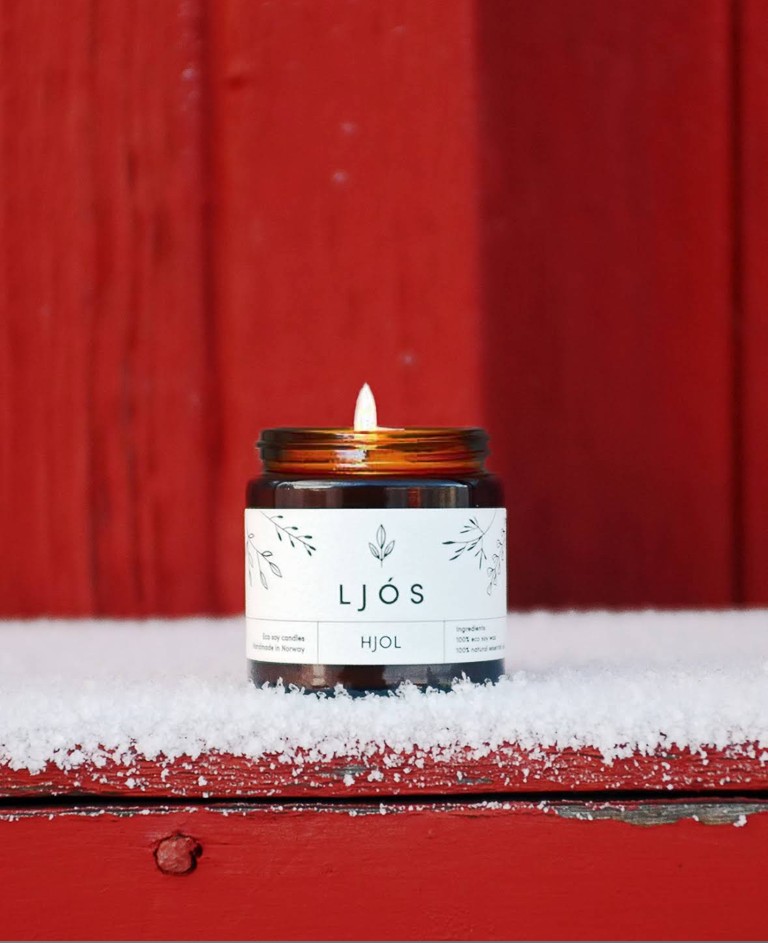 Ljós HJOL soyalys brenner i snø utenfor en tradisjonell rød norsk hytte i Olden, Norge – miljøvennlig håndlaget lys laget i Norge