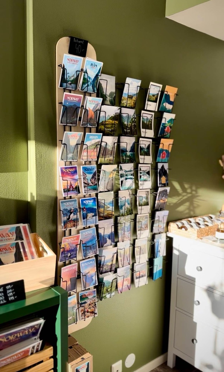 Veggutstilling av reisepostkort fra Norge til salgs i suvenirbutikk i Olden – med Flåm, Bergen, Trolltunga, Ålesund og norske fjordlandskap, priset til 40 kr
