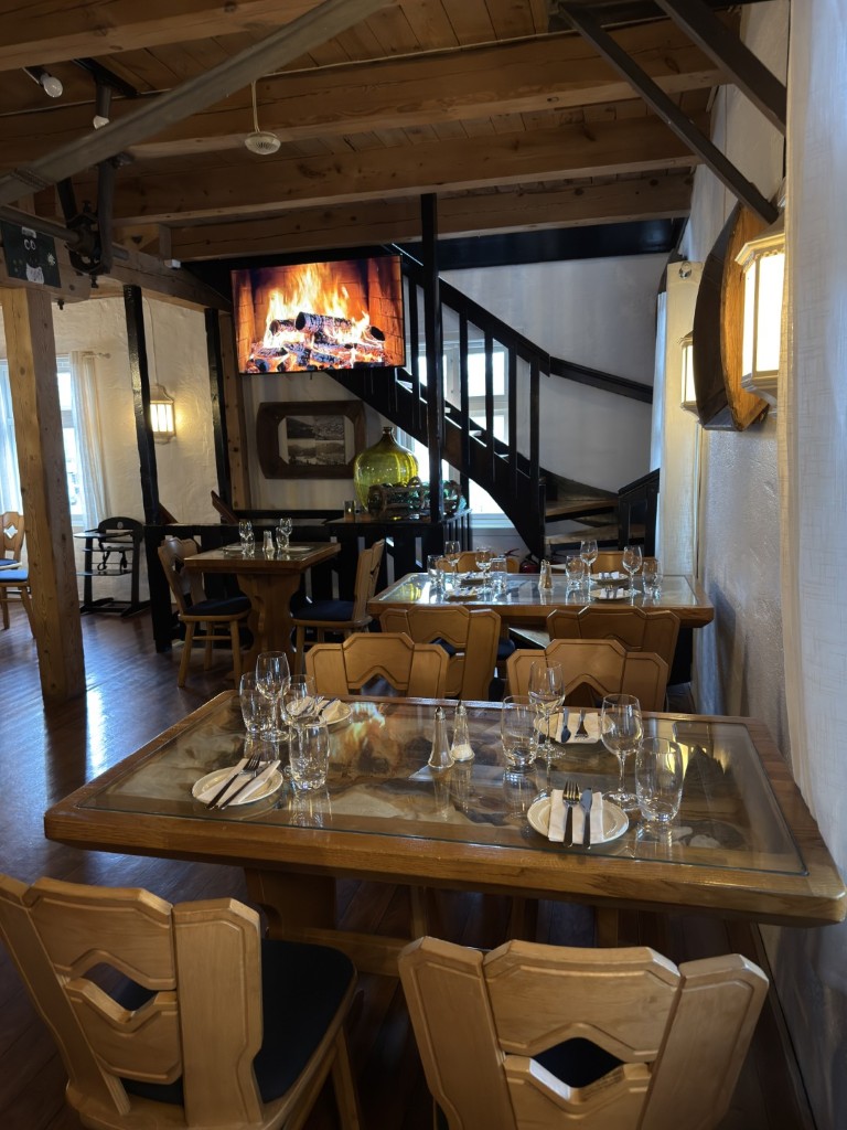 Hummus med grillet flatbrød, soltørkede tomater, ruccola og pinjekjerner servert utendørs på Mølla Gjestehus med cruiseskip i Oldenfjorden