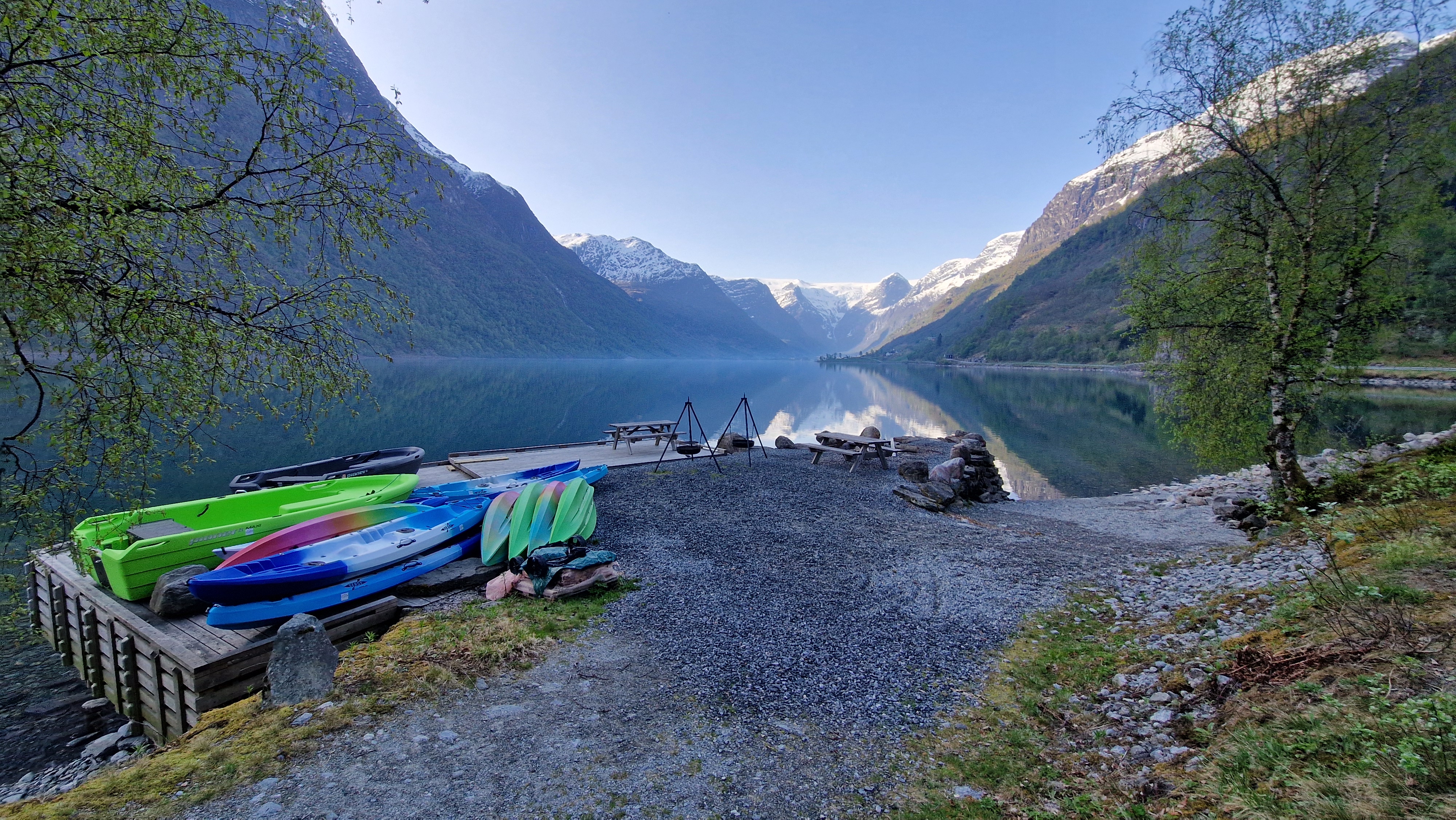 Kajakk- og kanoutleiebrygge ved Olden Camping ved Oldevatnet, med snødekte fjell og Briksdalsbreen speilet i rolig vann