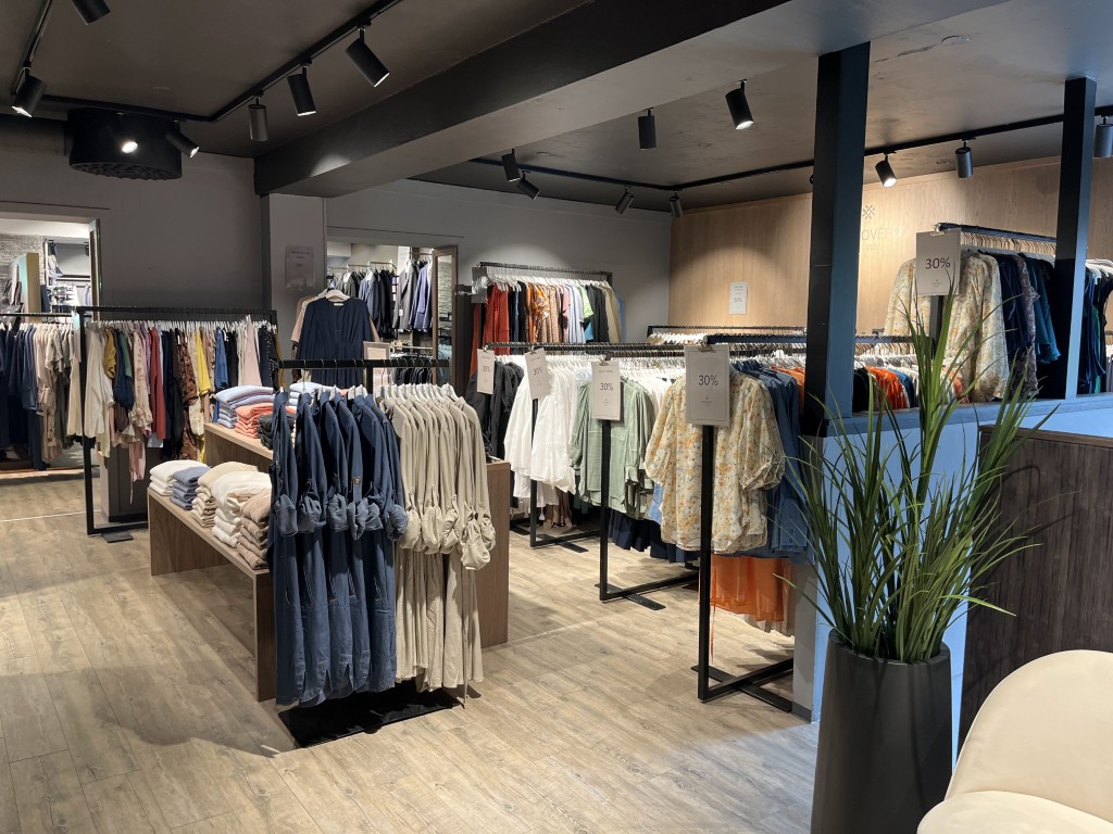 Riccovero dameklæravdeling i Olden med fargerike kjoler, bluser og strikkeplagg på skinner – motehandel nær de norske fjordene