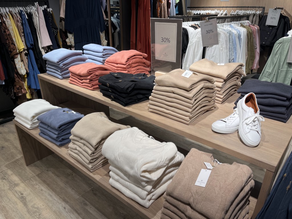 Utstilling av brettede strikkeplagg, gensere og fritidsklær hos Riccovero klesbutikk i Olden, Norge, med rabatter på outletsalg