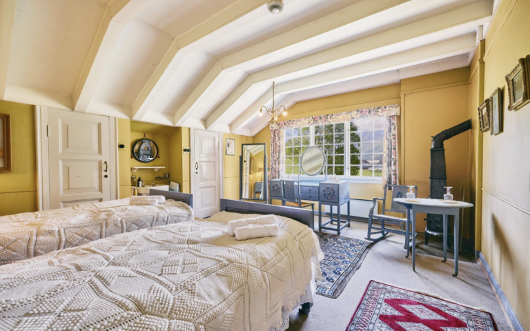 Sjarmerende vintage dobbeltrom på Singer gjestehus i Olden, Norge, med hvelvet tak, antikke møbler, vedovn og vindu med fjordutsikt